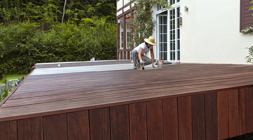 Woman paints terrace with terrace wood oil